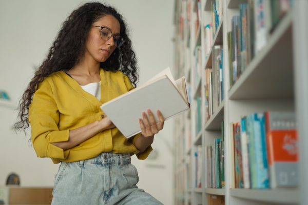 Latina Caucasian Hispanic woman learning teacher girl student female studying college browsing bookcase searching book read bookshelf looking literature library search textbook take find university. High quality 4k footage